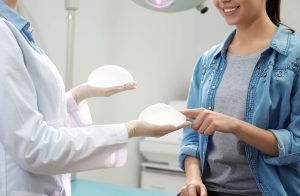 Two women in a doctor's office talking about breast implants.