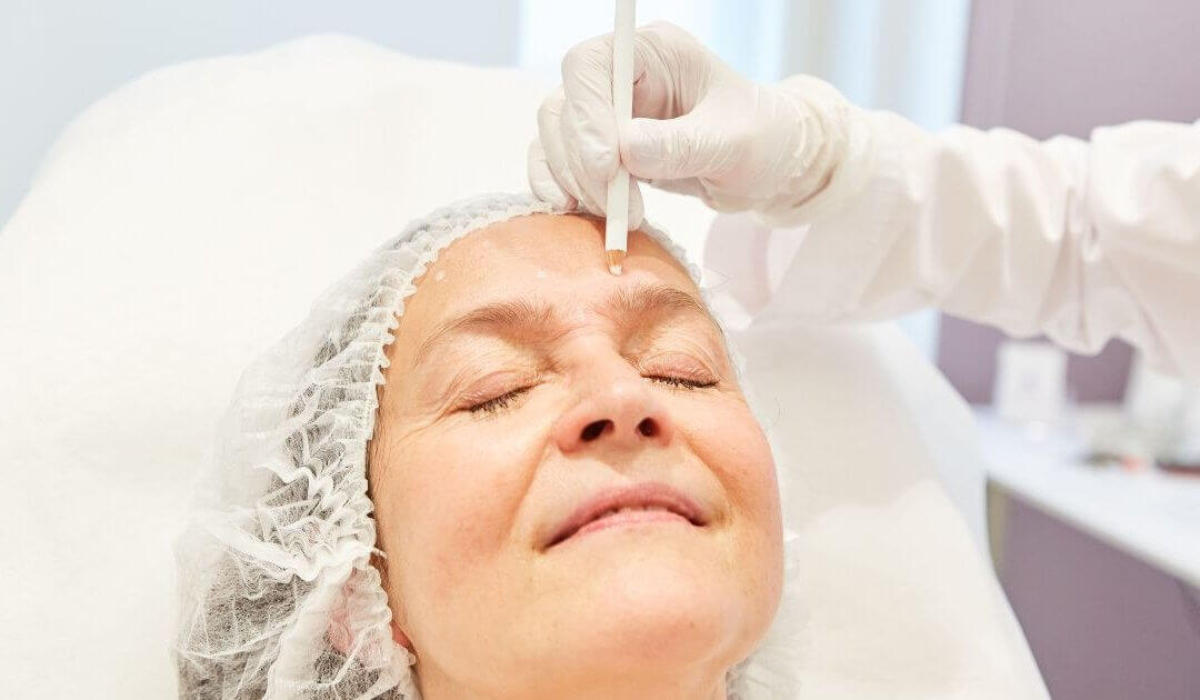 A person receives a mini facelift on their forehead in a clinical setting.